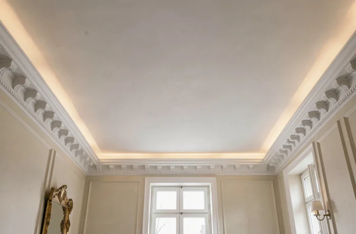 Gorge lumineuse LED dissimulée dans une corniche de staff en plâtre au plafond d'un salon classique